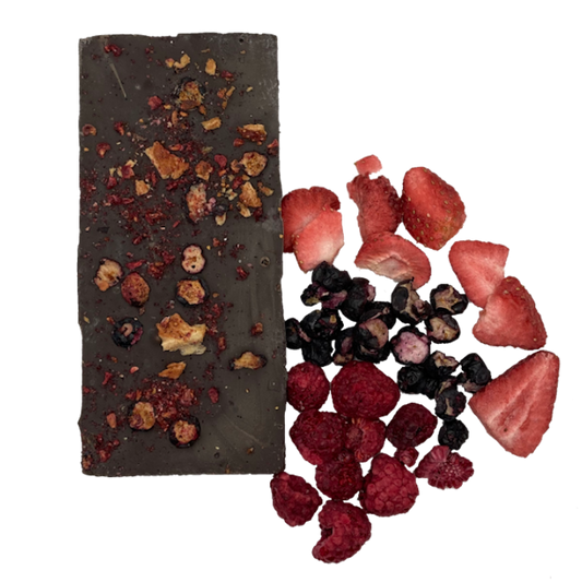 Chocolate bar covered in three berry types. The three berries, (strawberries, blueberries and raspberries) are next to it