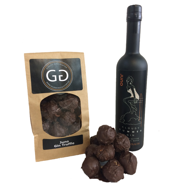 Pile of Juno Gin truffle next to a Giles chocolatier bag filled with scrumptious juno Gin truffles. Bottle of Juno gin is in the background