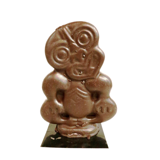 Three dimensional chocolate tiki sitting down, head cocked to one side and hands on it's knees