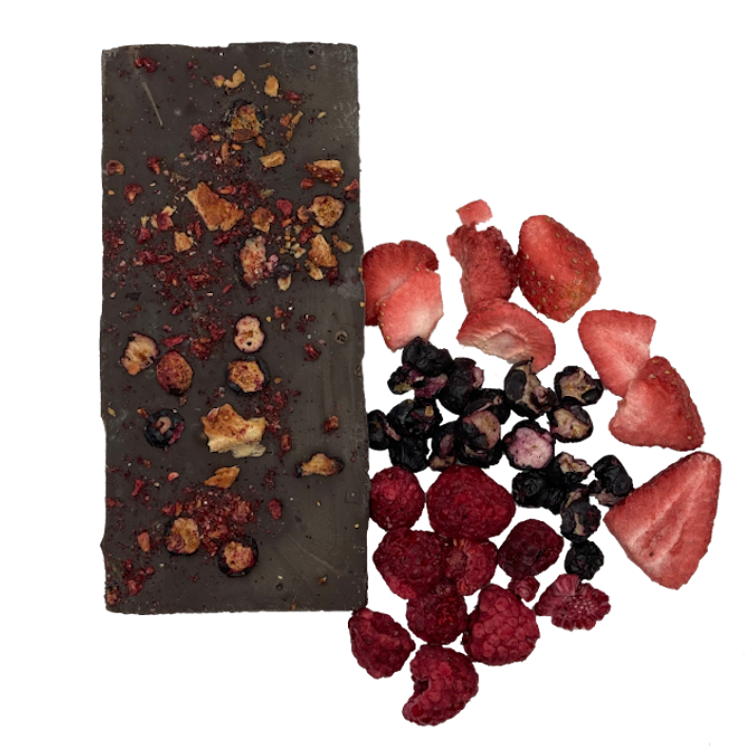 Chocolate bar covered in three berry types. The three berries, (strawberries, blueberries and raspberries) are next to it