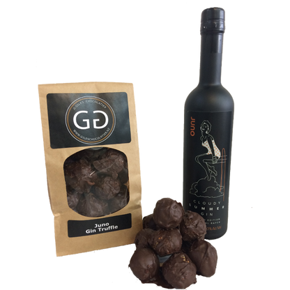 Pile of Juno Gin truffle next to a Giles chocolatier bag filled with scrumptious juno Gin truffles. Bottle of Juno gin is in the background