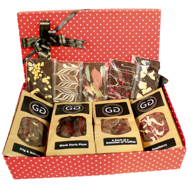 A red spotted box with lid and ribbon containing a mixture of Giles chocolatier bars and truffles